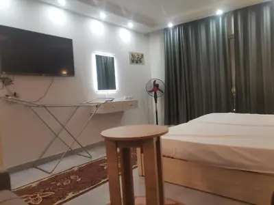 a bedroom with a bed and a flat screen tv at Modern Downtown Apartment In Scandic Resort WiFi Beach Front in Hurghada