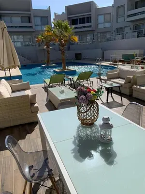 a table with a vase of flowers on top of a pool at 2bd direct on the main pool in Hurghada