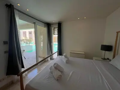 a white bed in a room with a large window at 2bd direct on the pool in Scarab El Gouna in Hurghada