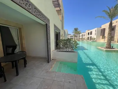 a swimming pool next to a building with a table at 2bd direct on the pool in Scarab El Gouna in Hurghada