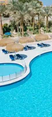 a swimming pool with blue water and chairs and palm trees at Apartment for daily rent free beach access in Hurghada