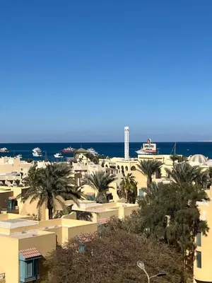 a city with buildings and palm trees and the ocean at Benashti Hurghada apartment in Hurghada