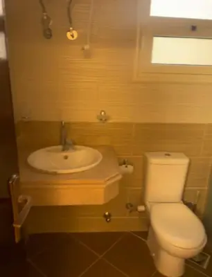 a bathroom with a white toilet and a sink at Balkan Beach Resort- Relaxing Beach Apartment in Hurghada