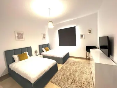 a bedroom with two beds and a flat screen tv at Luxury 2BR Sea View Apt in Azzurra Sahl Hasheesh in Hurghada