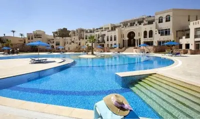 a person wearing a hat sitting in front of a swimming pool at Luxury 2BR Sea View Apt in Azzurra Sahl Hasheesh in Hurghada