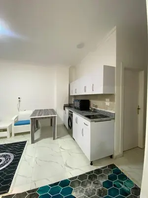 a kitchen with white cabinets and a table in a room at الكوثر in Hurghada