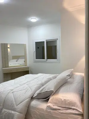 a white bedroom with a bed and a mirror at الكوثر in Hurghada