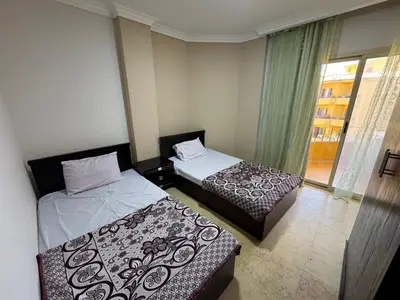 two beds in a small room with a window at 2 bedroom furnished apartment in Hurghada