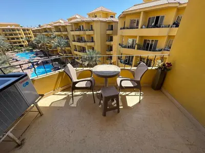 a balcony with a table and chairs and a pool at 2 bedroom furnished apartment in Hurghada