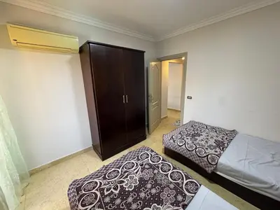 a bedroom with two beds and a closet and a bedskirts at 2 bedroom furnished apartment in Hurghada