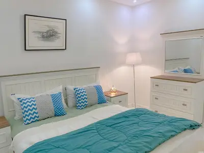 a white bedroom with a bed with blue pillows at Bright 2BR & Office, Remote Work Ready & Long Stays in Hurghada