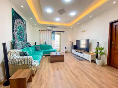 a living room with a green couch and a television at Bright 2BR & Office, Remote Work Ready & Long Stays in Hurghada