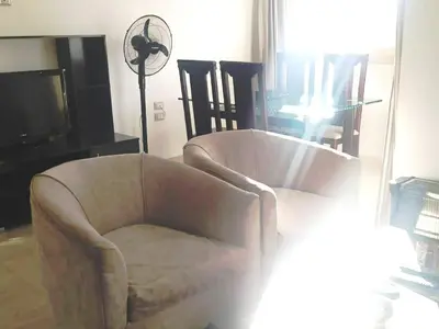a living room with a chair and a television at Arietta Flat Amazing location in Avrio compound in Hurghada