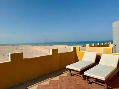 a balcony with two chairs and a view of the beach at Stunning Pool and Sea View Villa, Al Dora Resort, Hurghada in Hurghada