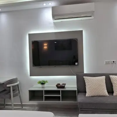 a living room with a couch and a tv on a wall at Luxury Apartment Pool&Private Beach in Hurghada