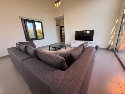 a living room with a couch and a flat screen tv at Luxury 2 BR Villa with garden - Baywest - somabay in Hurghada