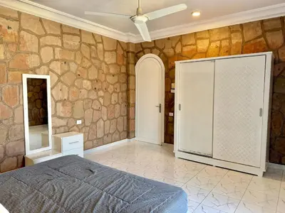 a bedroom with a bed and a stone wall at Nile Palace Villa in Luxor