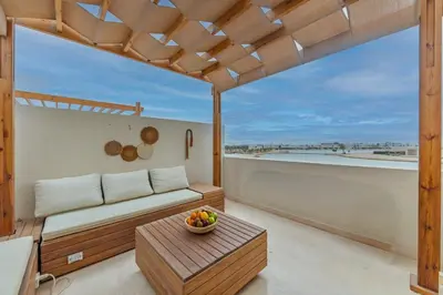 a balcony with a couch and a bowl of fruit on a table at Amazing Sunset View Apartment with modern style in Hurghada