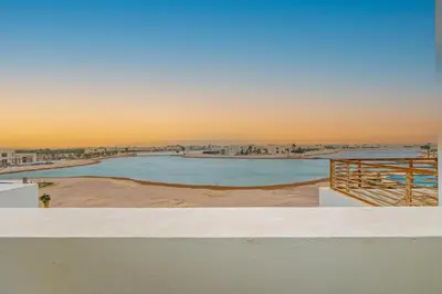 a large swimming pool with a sunset in the background at Amazing Sunset View Apartment with modern style in Hurghada