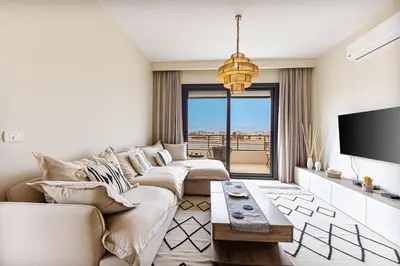 a living room with a couch and a tv at Amazing Sunset View Apartment with modern style in Hurghada