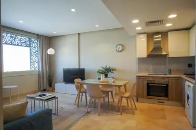 a kitchen and living room with a table and chairs at Mangroovy Beach Front - 1 BR - Free Beach & Pool access in Hurghada