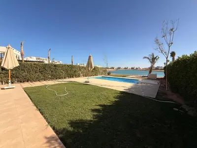 a yard with a pool and a lawn with an umbrella at El Gouna Ancient Sand Villa 3 Bedroom & Nanny in Hurghada