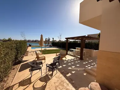 a patio with chairs and a table and a umbrella at El Gouna Ancient Sand Villa 3 Bedroom & Nanny in Hurghada