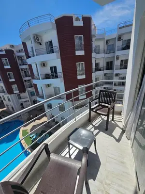 a balcony with two benches and a swimming pool on a apartment at Aqua palms resort 2 bed flat C409 in Hurghada