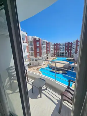 a balcony with two chairs and a swimming pool at Aqua palms resort 2 bed flat C409 in Hurghada