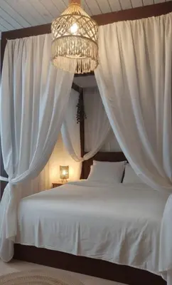 a bedroom with a white bed with curtains and a chandelier at Amber Dahabiya in Luxor