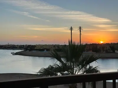 a sunset over a body of water with a palm tree at Blue haven el gouna in Hurghada