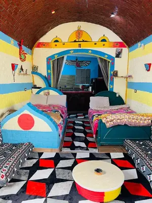 a room with two beds and a table in it at Marwa House an Authentic Mud-Brick Home in Al Aqālitah