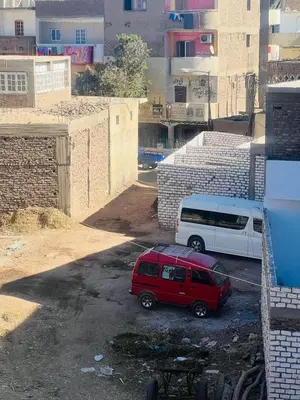 a red van parked next to a white van at Marwa House an Authentic Mud-Brick Home in Al Aqālitah