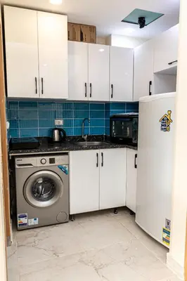 a kitchen with white cabinets and a washing machine at Mirage Bay Resort Hurghada C-781 in Hurghada