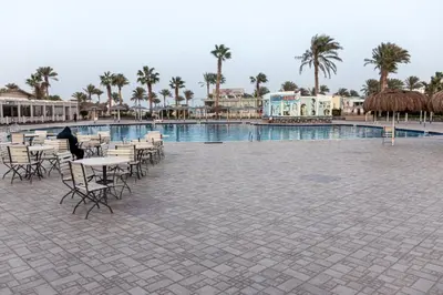 a swimming pool with tables and chairs and palm trees at Mirage Bay Resort Hurghada B-780 in Hurghada