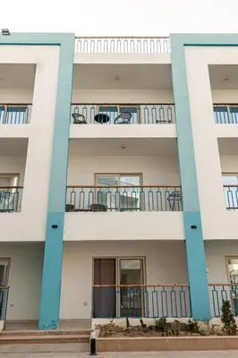 an apartment building with blue balconies and tables at Mirage Bay Resort Hurghada A-775 in Hurghada