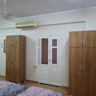 a room with a bed and wooden cabinets and a window at Julia's Guest House in Shellal