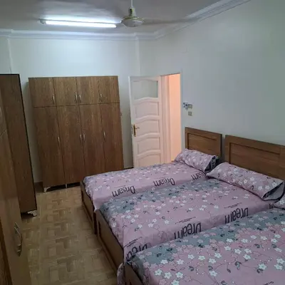 a bedroom with two beds and wooden cabinets at Julia's Guest House in Shellal