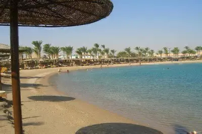 a beach with umbrellas and people in the water at Mirage Bay Resort Hurghada B-794 in Hurghada