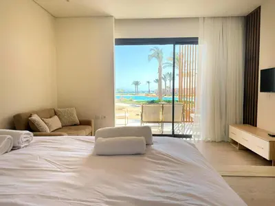 a bedroom with a white bed with a view of the beach at Pool front Mesca Cabana Minutes to Sandy Beach in Soma bay in Hurghada