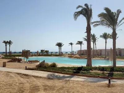 a swimming pool with palm trees in a resort at Pool front Mesca Cabana Minutes to Sandy Beach in Soma bay in Hurghada