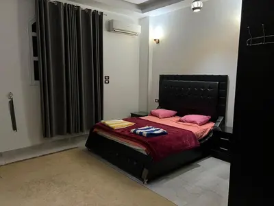 a bedroom with a black bed with pink pillows at The Palace Guesthouse in Luxor