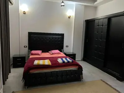 a bedroom with a large black bed with pink pillows at The Palace Guesthouse in Luxor