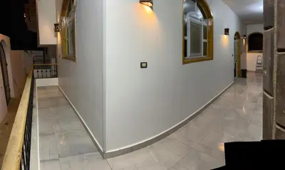 a hallway with a white wall and a tile floor at The Palace Guesthouse in Luxor