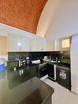 a kitchen with white cabinets and black appliances at 2 bedroom flat with balcony in Hurghada