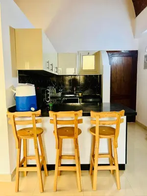 a kitchen with three wooden chairs and a counter top at 2 bedroom flat with balcony in Hurghada