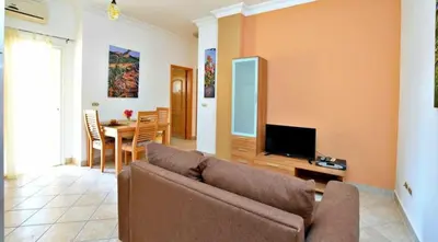 a living room with a couch and a dining room at Iris Holiday Apartament in Hurghada