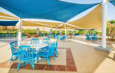 a patio with blue tables and chairs under a tent at Pyramisa Island Hotel Aswan in Aswan