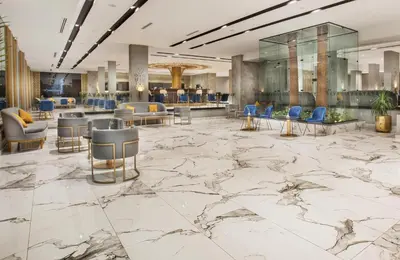 a lobby with a marble floor and blue chairs at Pyramisa Hotel Luxor in Luxor