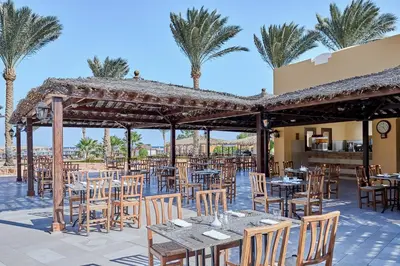 a restaurant with tables and chairs and palm trees at JAZ Solaya in Coraya Bay